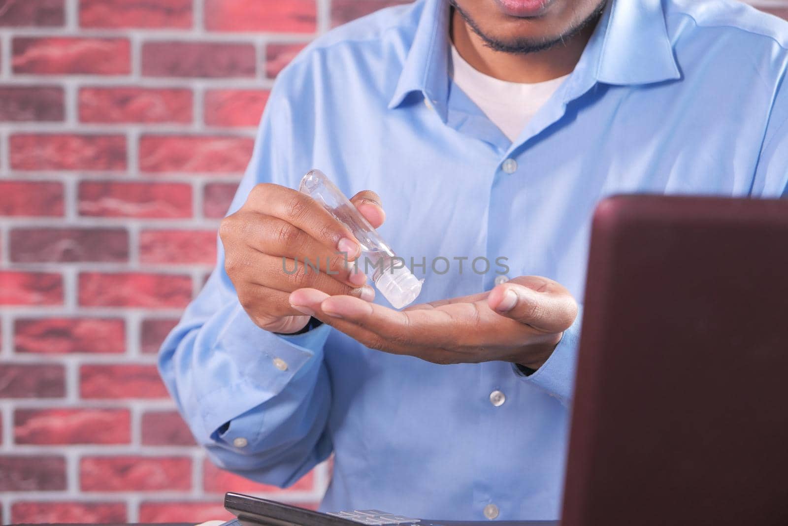 businessman using sanitizer gel on on office desk.