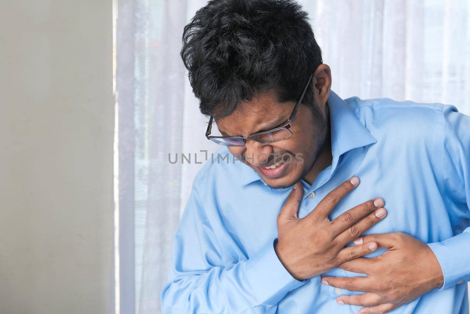 young man suffering pain in heart and holding chest with hand .