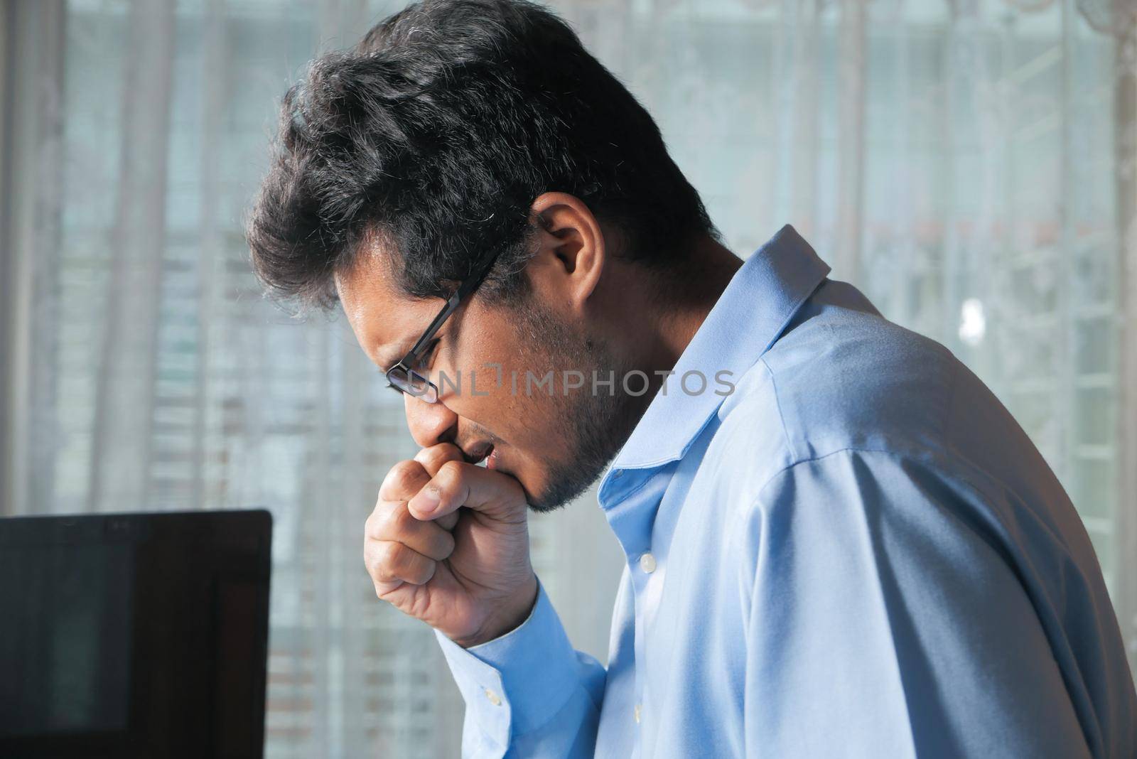 young sick businessman coughing while working on laptop .