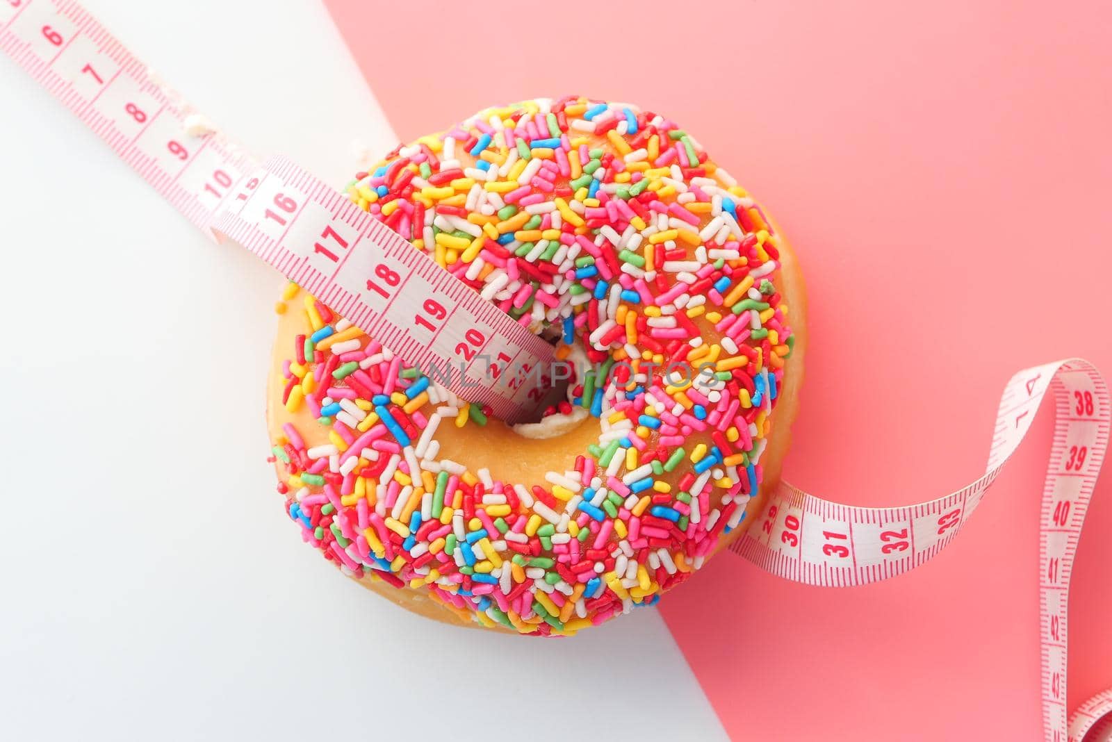 Close up of donuts and measurement tape on pink background