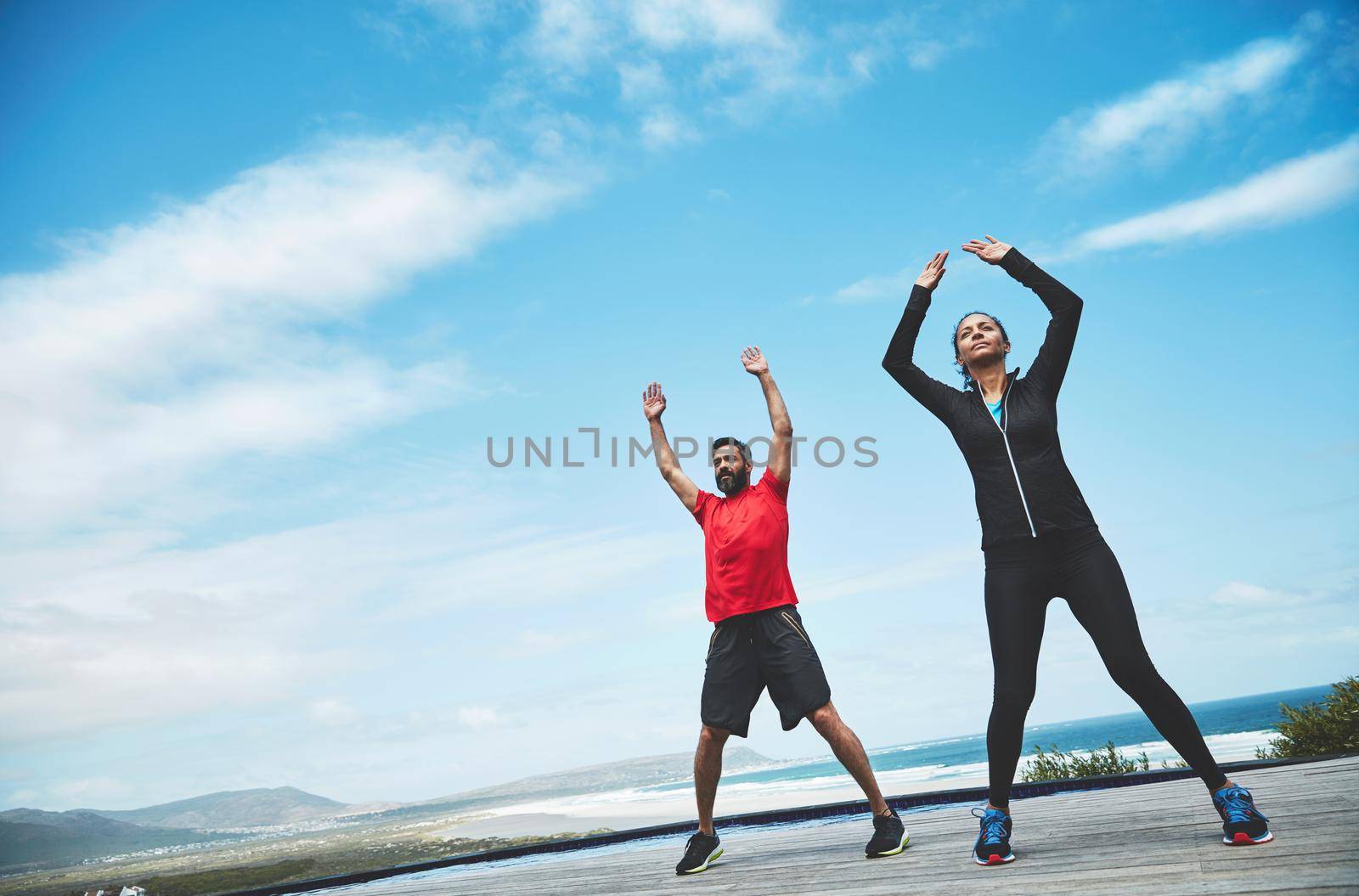 The outdoors enhances yoga. a couple doing yoga outdoors