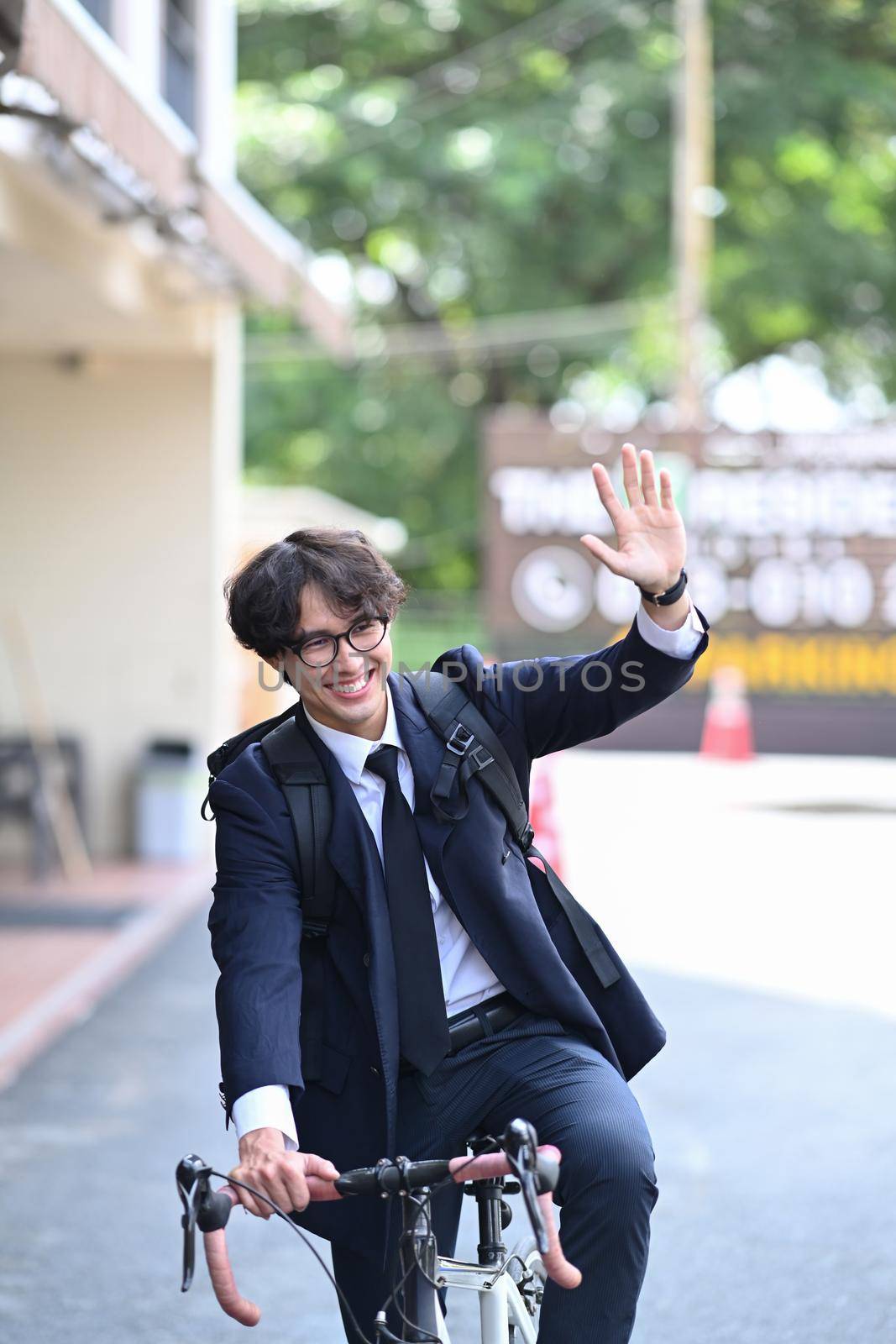 Happy businessman riding bicycle to work on city street in the morning. Eco Transportation and healthy active lifestyle concept. by prathanchorruangsak