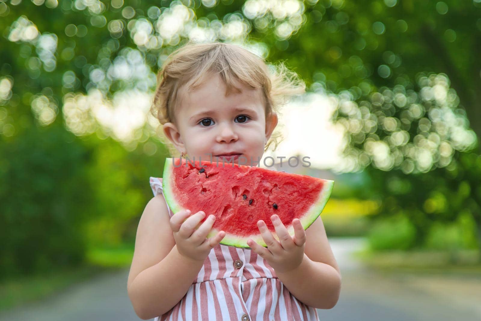 Child girl eats watermelon in summer. Selective focus. by yanadjana