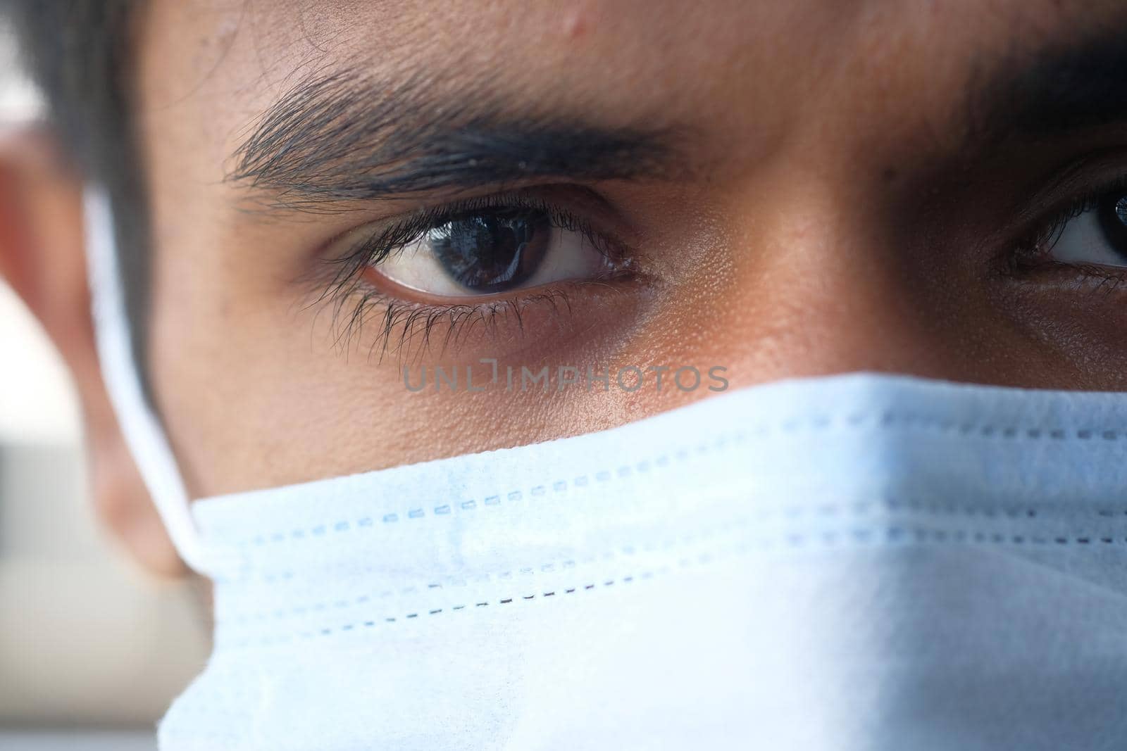 Close up of man with protective face mask looking at camera.