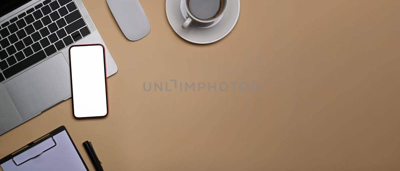 Top view smart phone with blank screen, laptop computer and coffee cup on beige background.