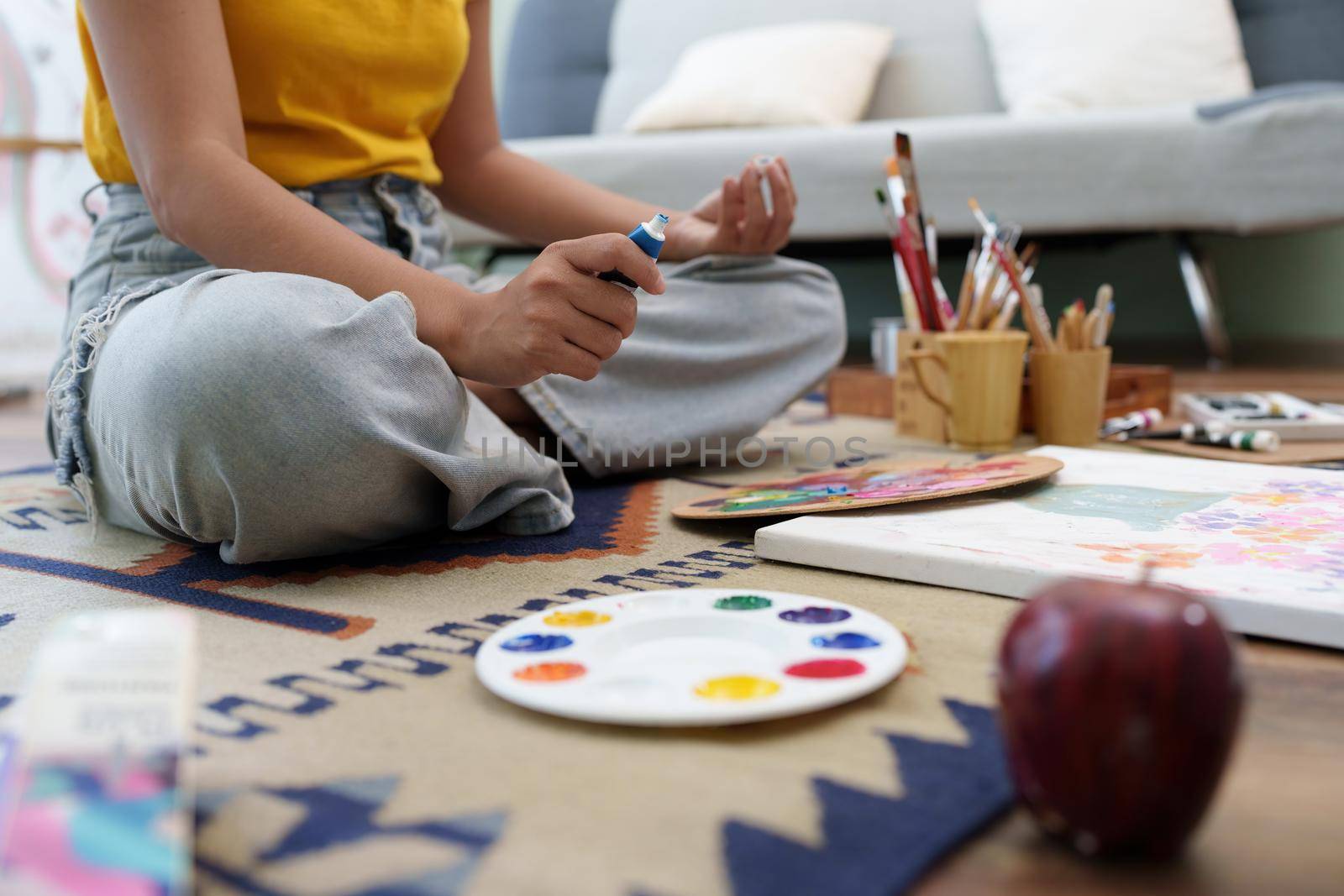 Joyful young female artist painting on canvas at workshop.