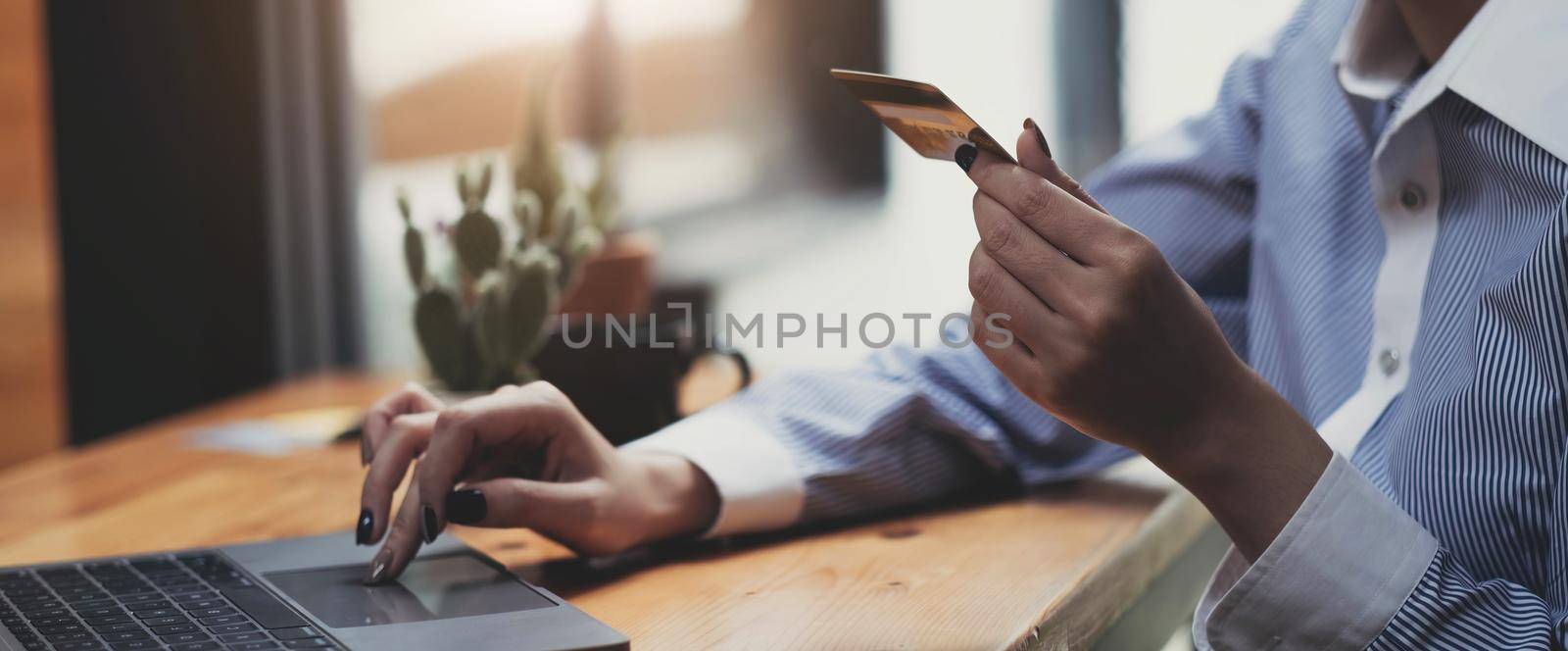 Hands holding credit card, typing on the keyboard of laptop, onine shopping detail close up.