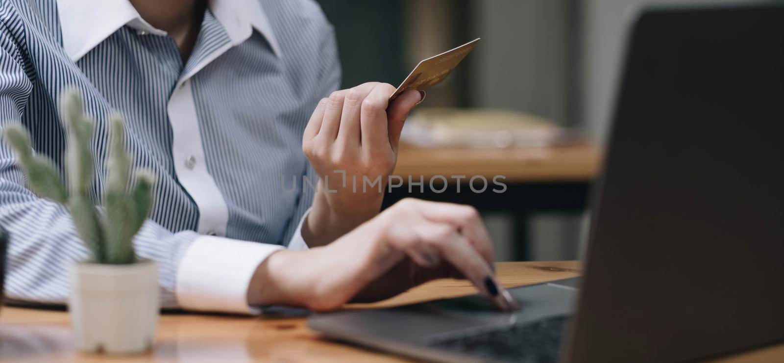 Hands holding credit card, typing on the keyboard of laptop, onine shopping detail close up.