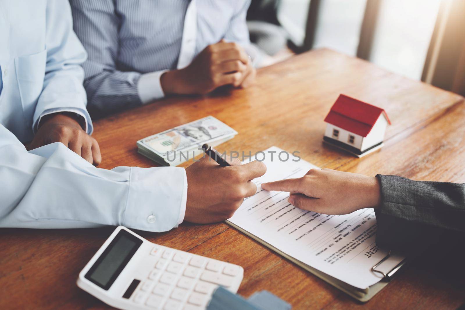 A couple is reading a home purchase contract before signing documents with a real estate agent by Manastrong