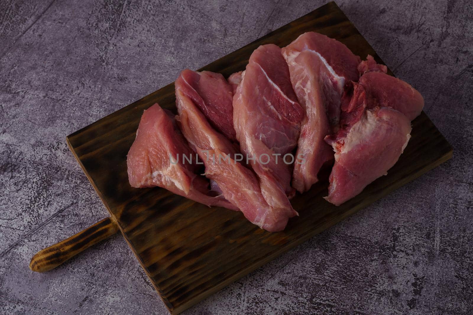 close-up of a filleted raw pork tenderloin on a wooden board