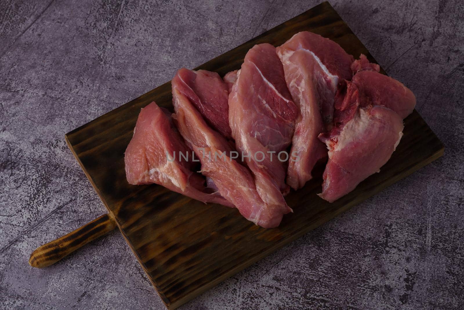 filleted raw pork tenderloin on a wooden board by joseantona