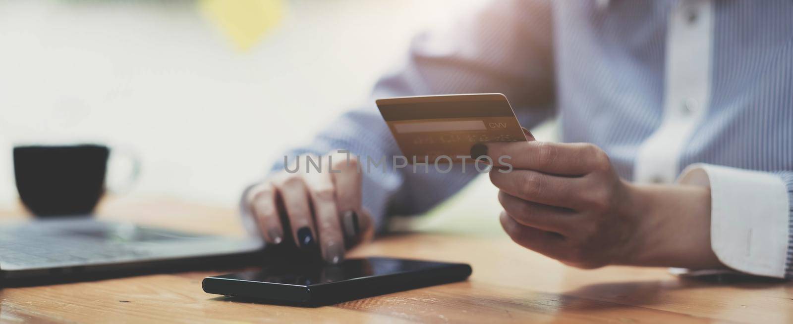 Hands holding credit card and using mobile smart phone with morning, Online shopping..
