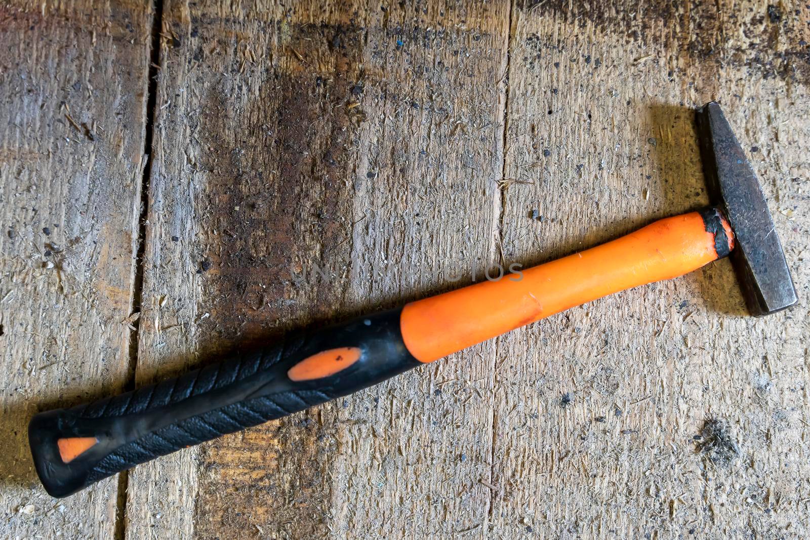 a small iron hammer with a long plastic handle for neat precise work on a wooden background in the workshop. Old used locksmith tools. Close-up. Copy space