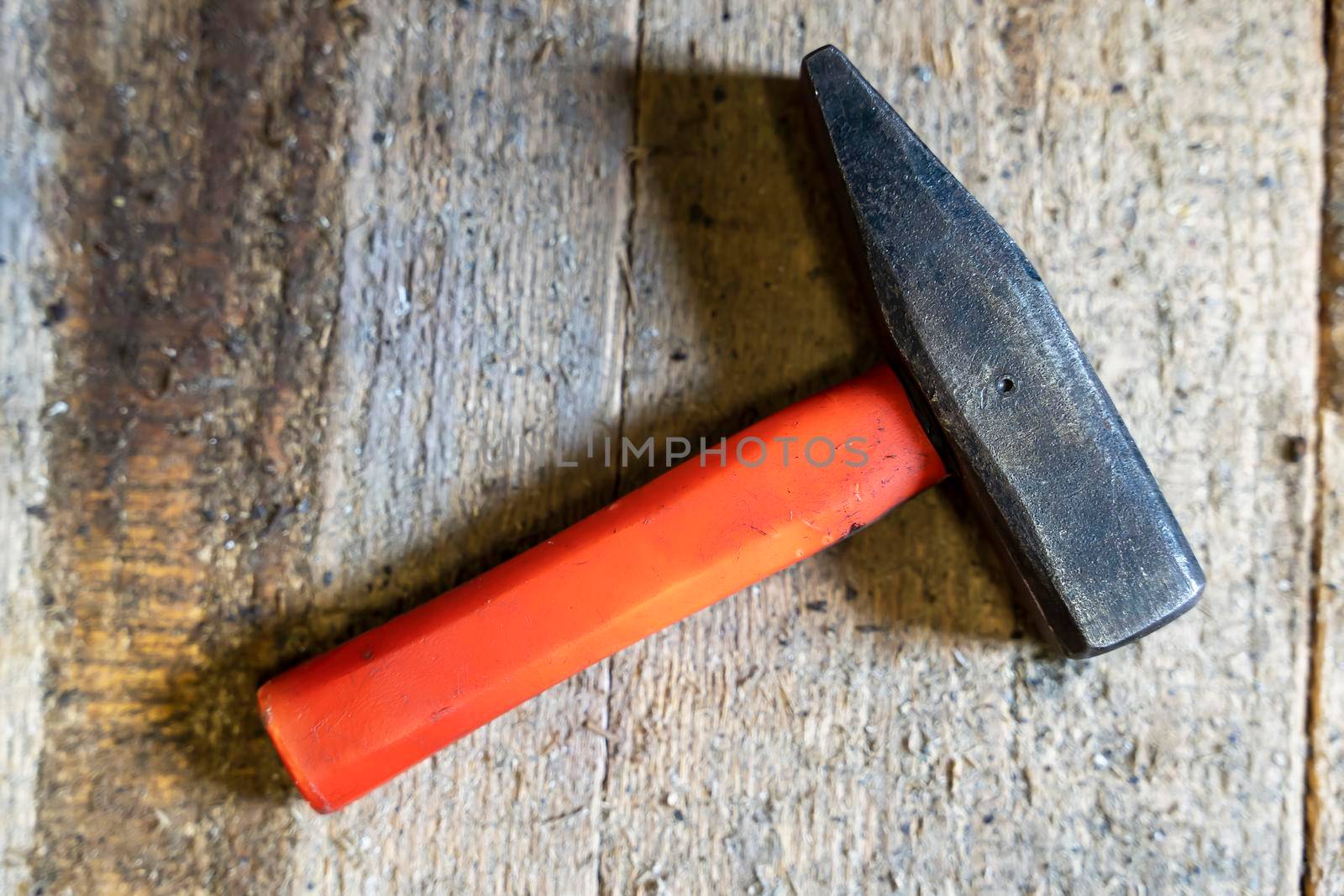 iron hammer with a short plastic handle on a wooden background in the workshop. Old used locksmith tools. Close-up. Copy space