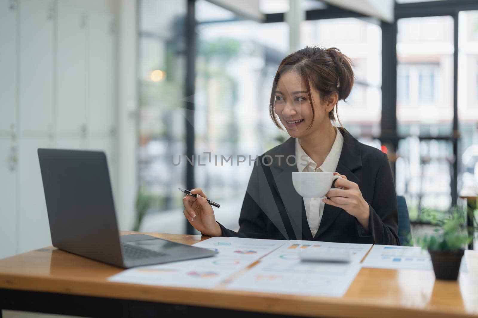 Portrait of asian business woman using laptop computer for financial analysis. by nateemee