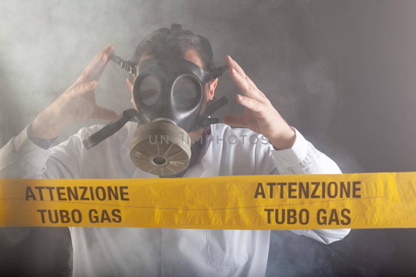 A medical engineer wearing an antigas mask during the gas leaks crisis and the emergency during the chaos. On the yellow tape the written notice "attention gas tube"