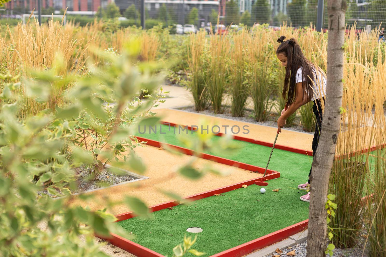 Cute little girl playing mini golf in a park