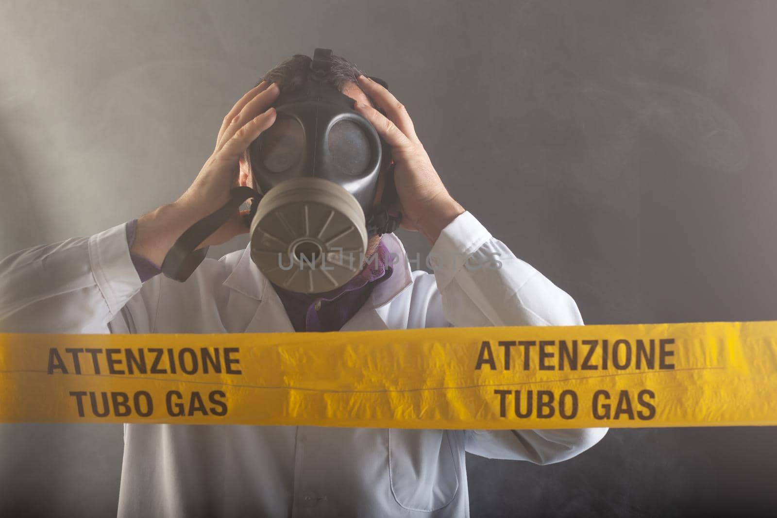 A medical engineer wearing an antigas mask during the gas leaks crisis and the emergency during the chaos. On the yellow tape the written notice "attention gas tube"