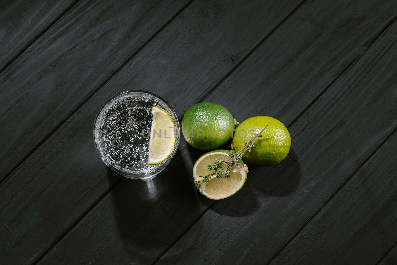 gin and tonic with citrus fruit and thyme on a black background.