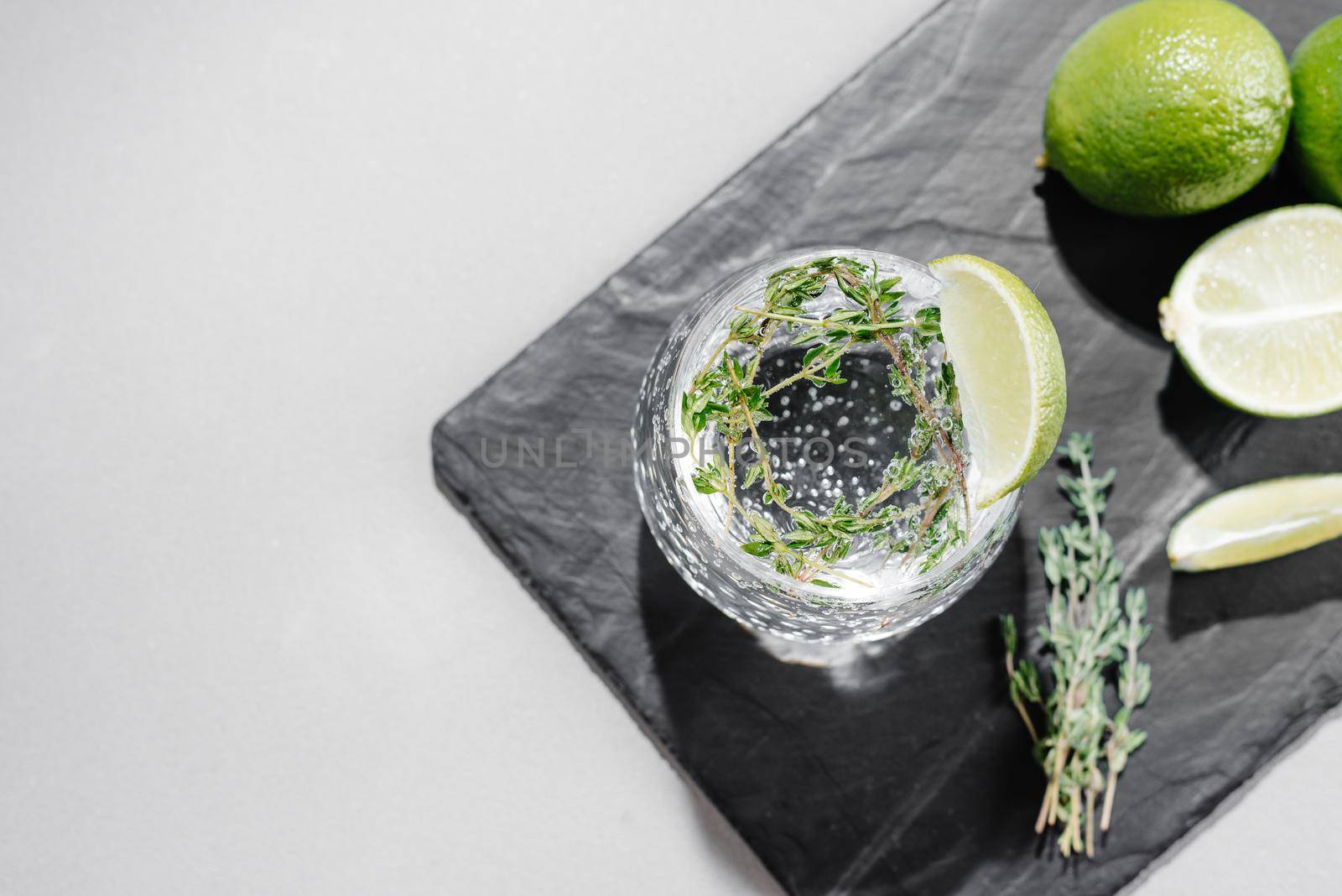 Tonic with lime and thyme. Cocktail on a gray background. Flashy food. Top view