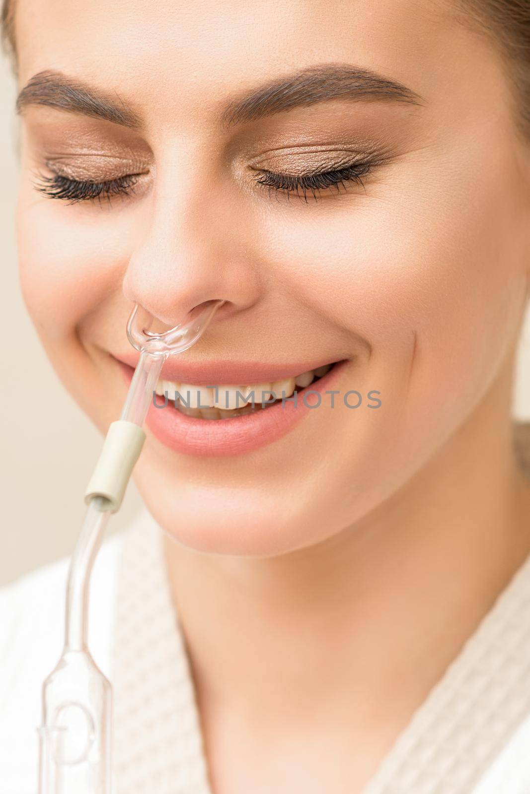 Beautiful happy young caucasian woman receiving nasal inhaler with essential oil smiling in a spa