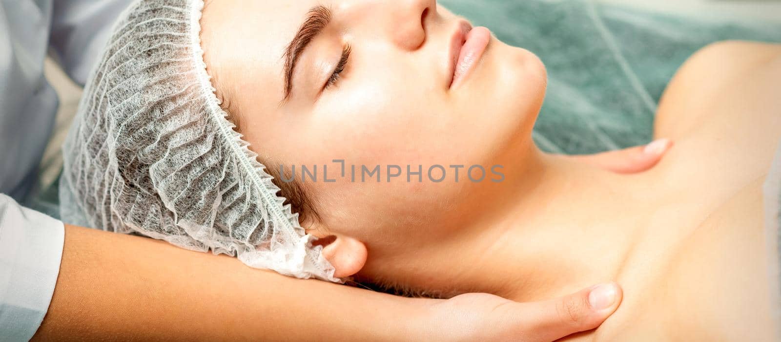 Side view hands of female therapist making massage of neck and shoulders to young caucasian woman in spa beauty salon