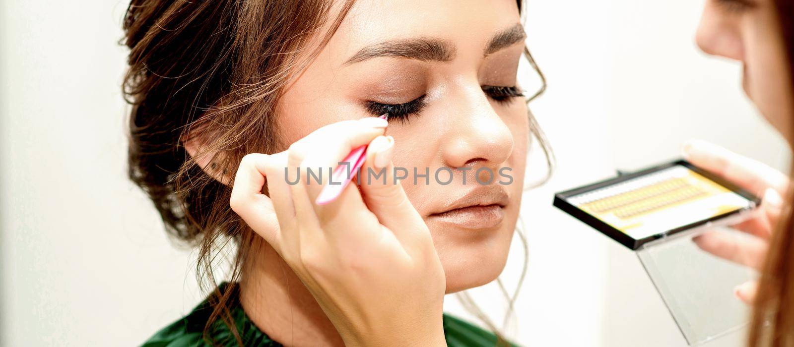 Young woman receiving eyelash extensions by okskukuruza