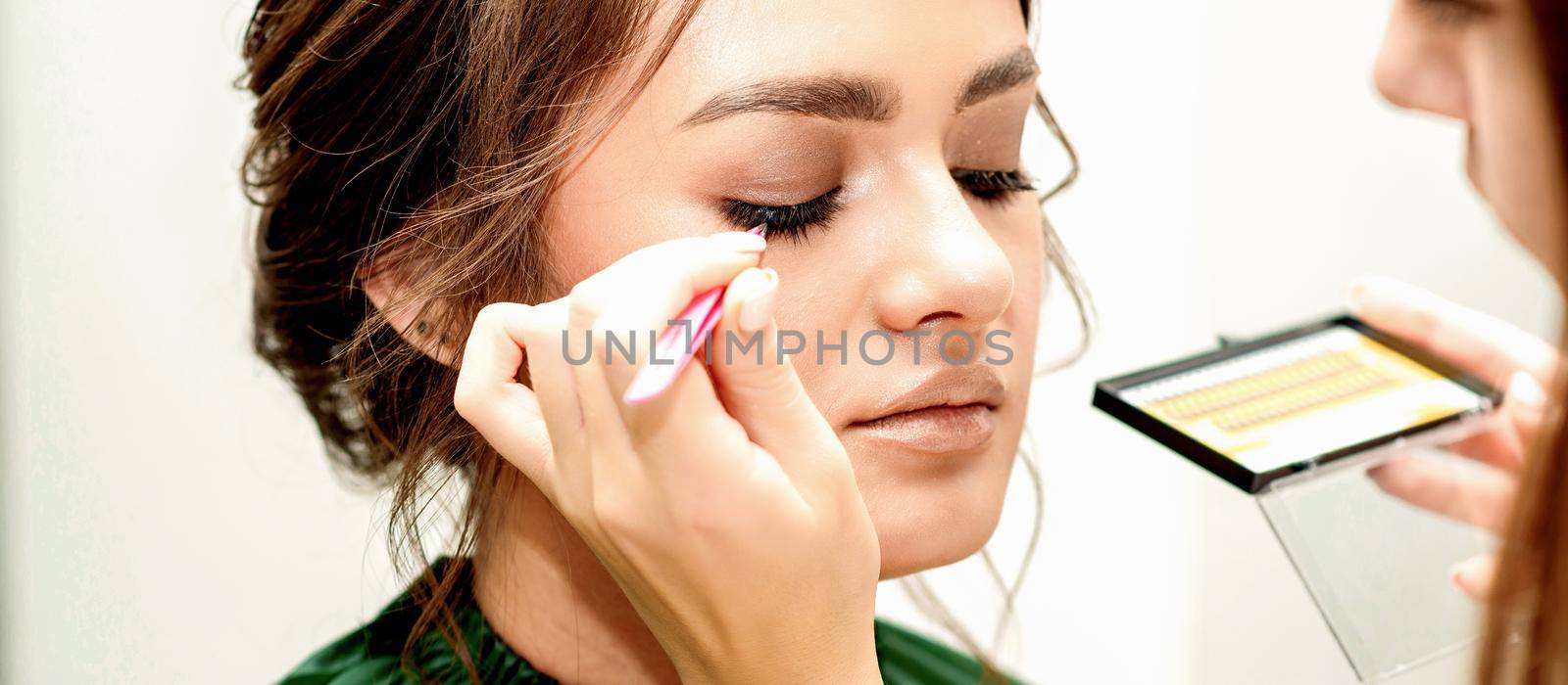 Eyelash extension procedures. Beautiful young caucasian woman receiving eyelash extension by master in a beauty salon