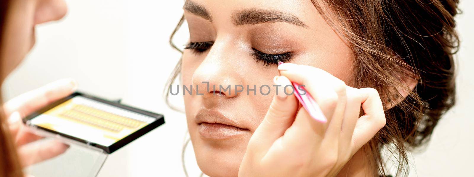 Eyelash extension procedures. Beautiful young caucasian woman receiving eyelash extension by master in a beauty salon