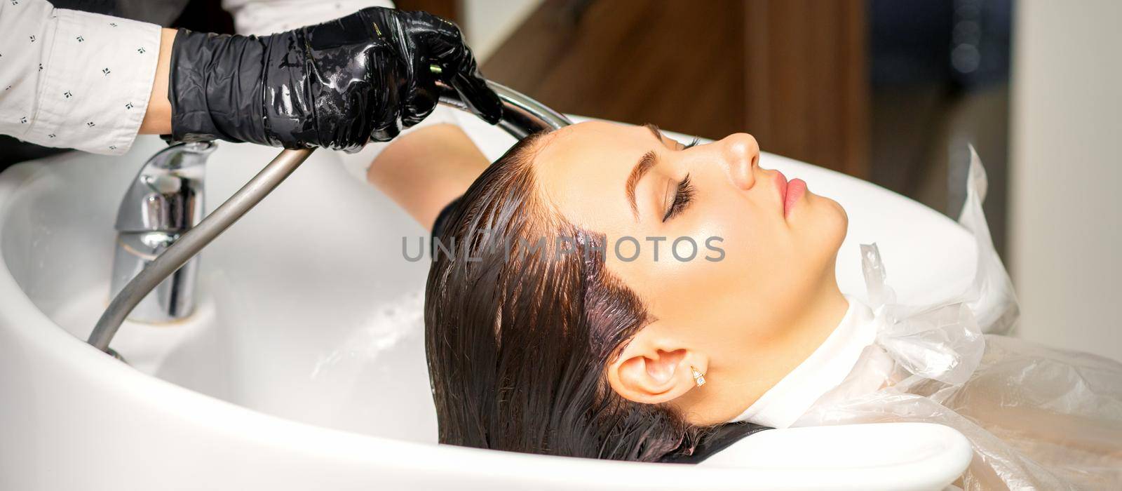Hairdresser washing hair of client by okskukuruza