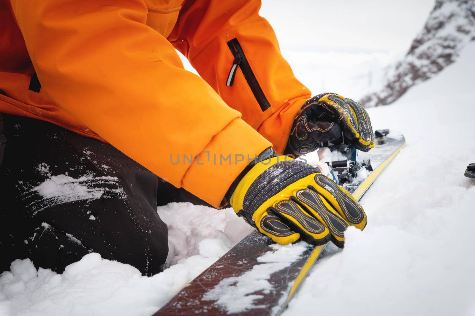 Close-up of a man's hand, adjusting the skis against the background of snow and things, putting on the skins on the track. Ski touring theme in the mountains.