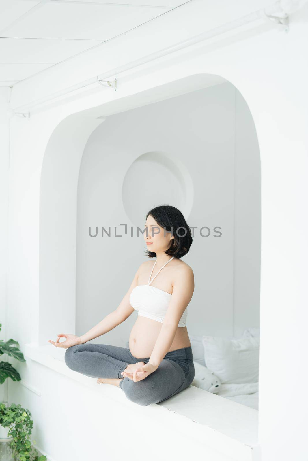 Pregnant young woman doing yoga at home by makidotvn