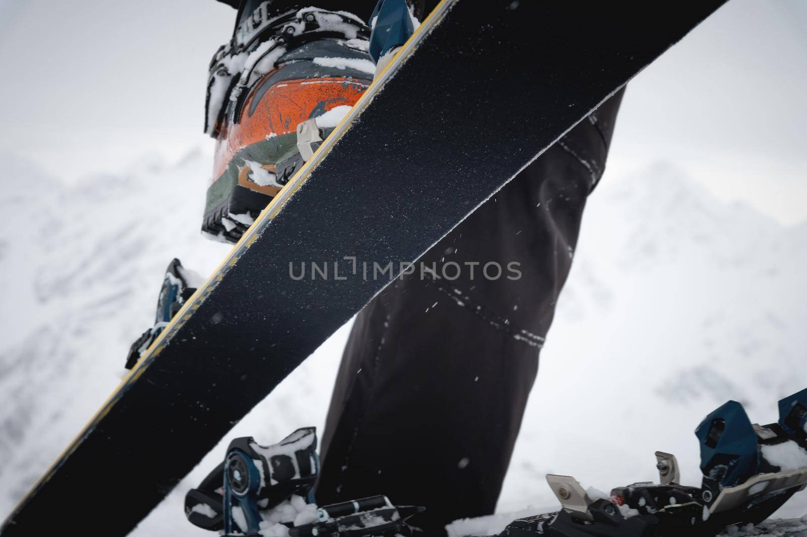 Close-up of a man's hand, adjusting the skis against the background of snow and things, putting on the skins on the track. Ski touring theme in the mountains.