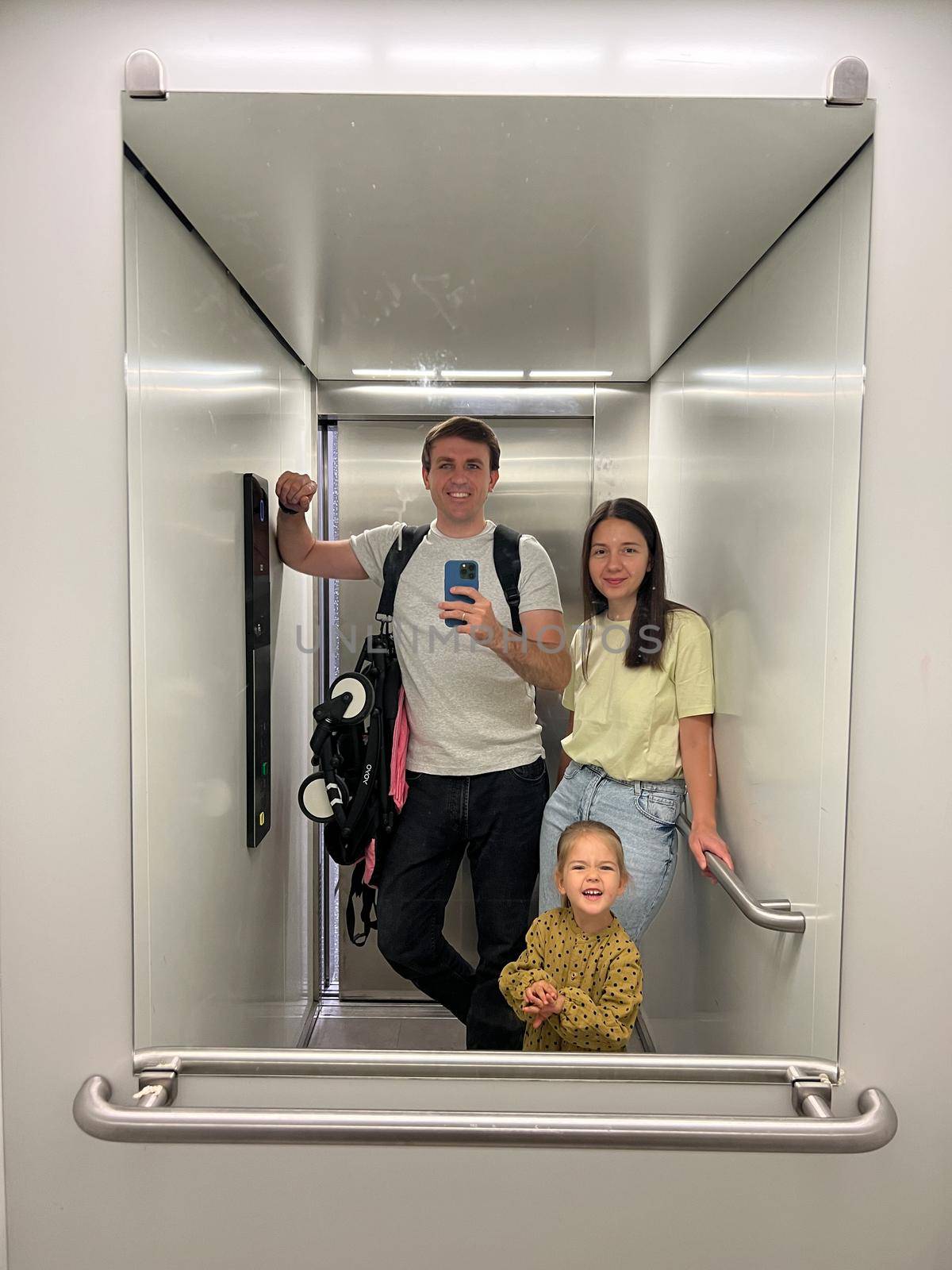 Mom, dad and little girl take pictures in the elevator. High quality photo