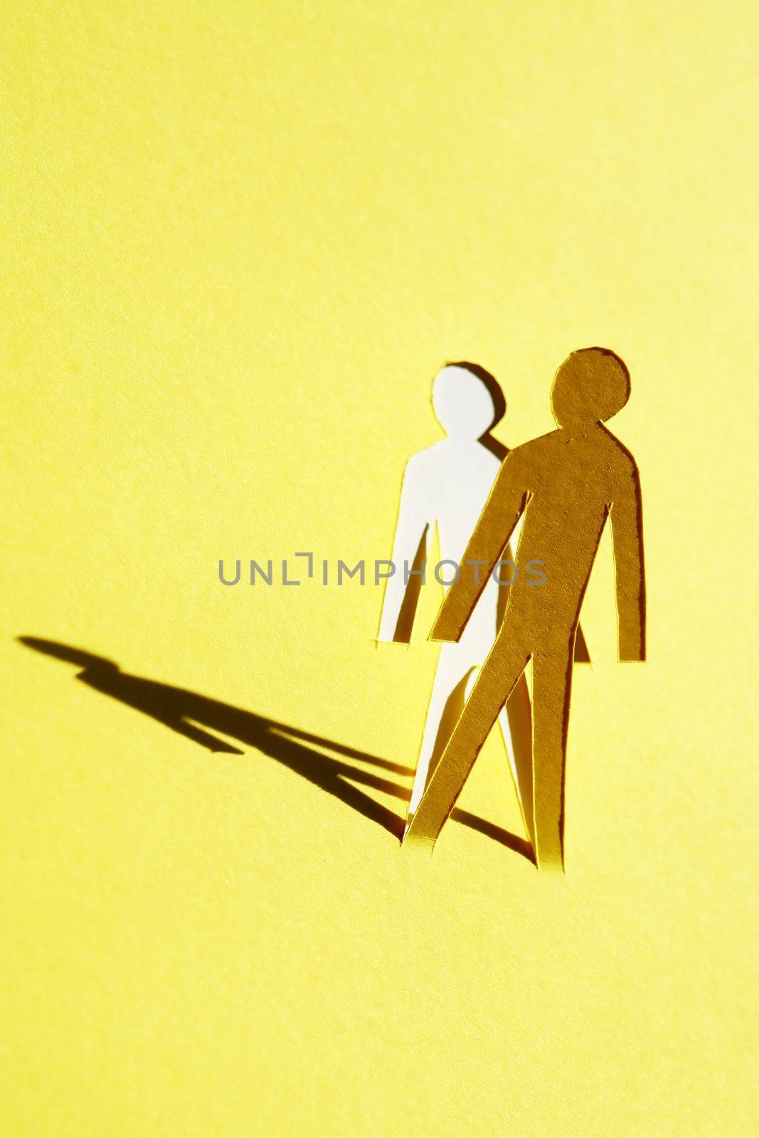 Man figure cutting from yellow paper with long shadow