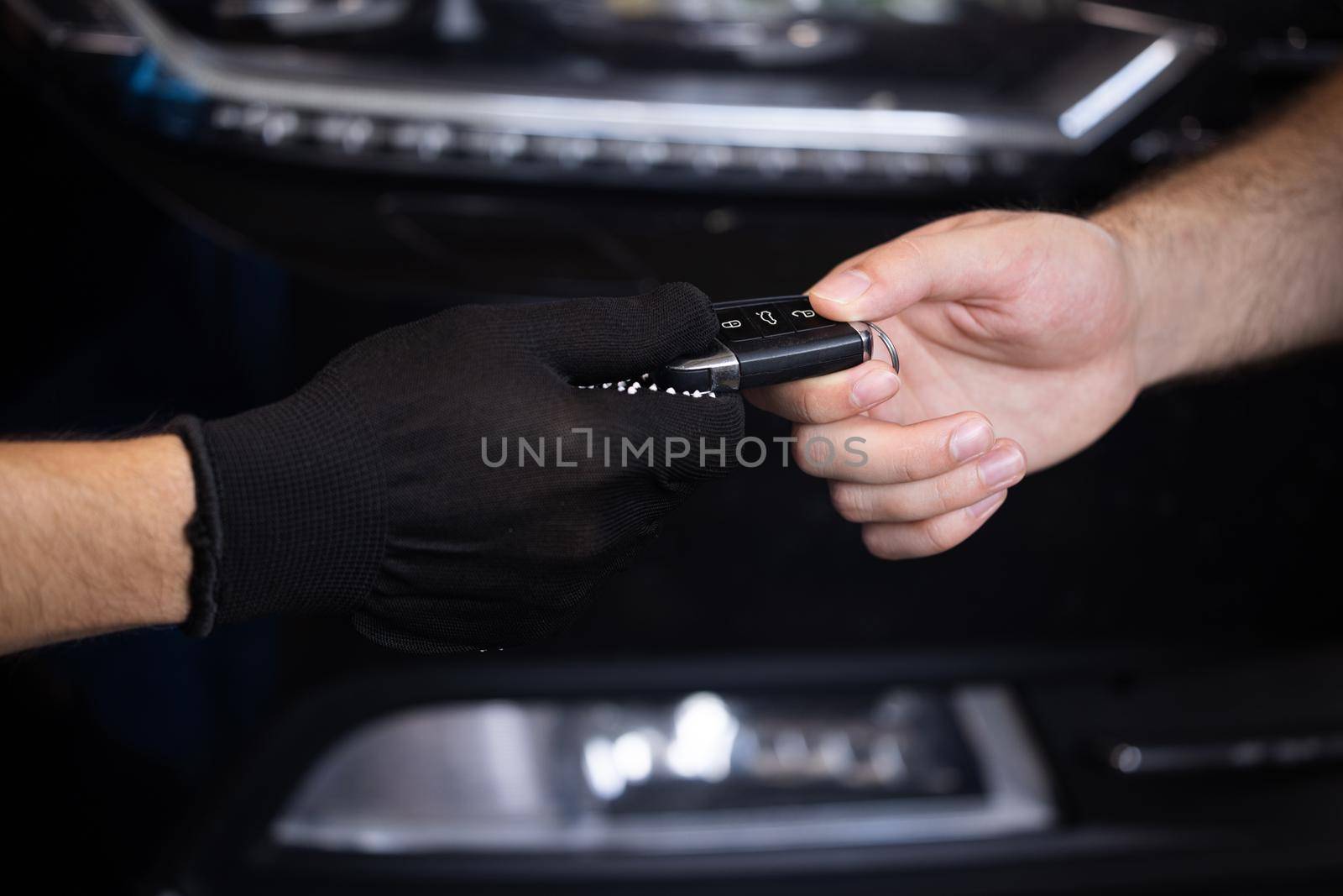 Car repair. Man owner of the auto gives the keys to the car repairman. Vehicle breaks down. Close up shot of hands of male client giving car key to mechanic in auto repair shop