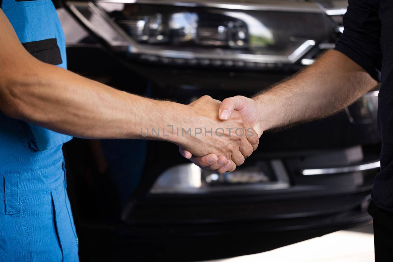 Automotive mechanic repairman handshake with client in garage. Vehicle service manager working in mechanics workshop. Success after check and maintenance car engine for customer. Car repair by uflypro