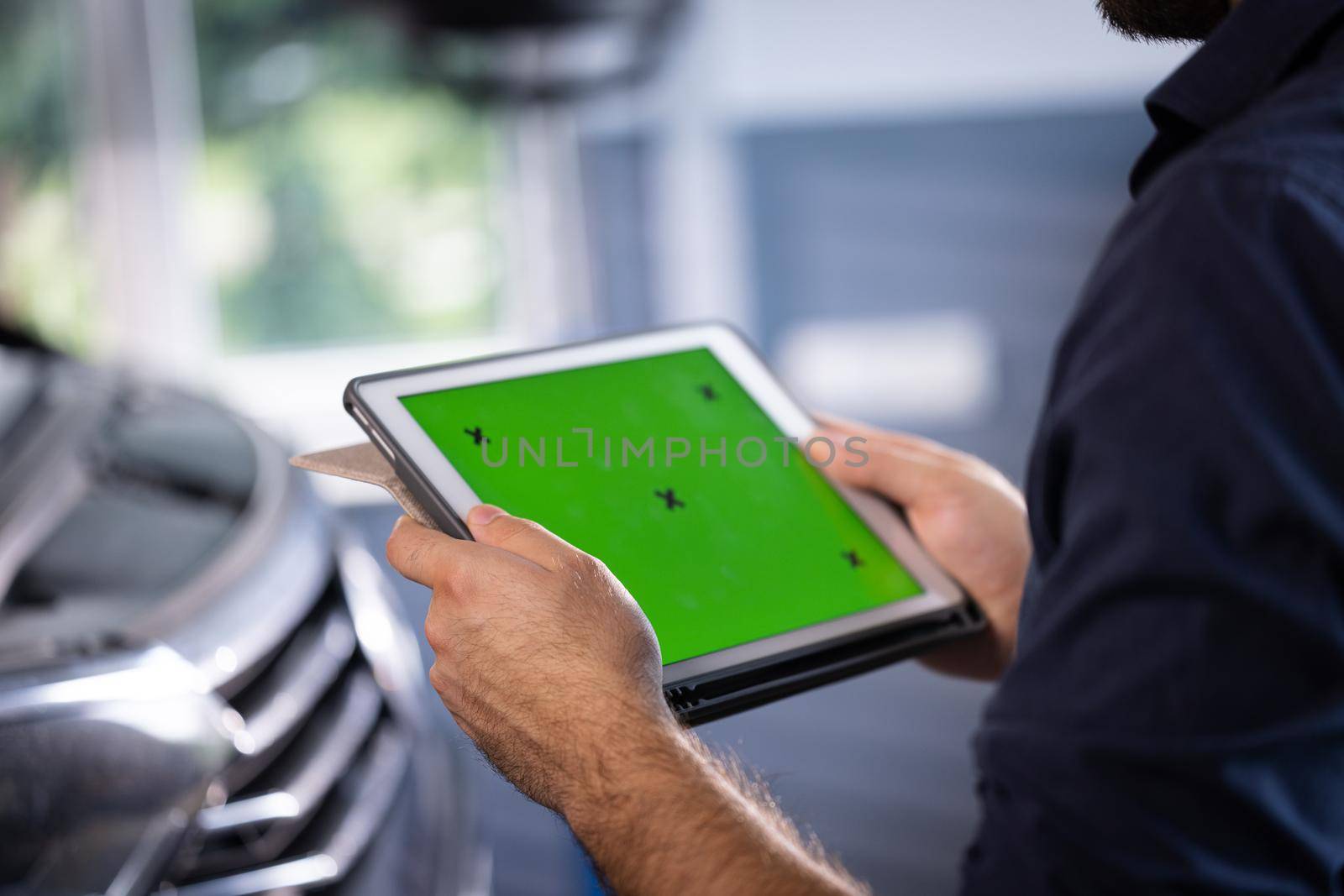 Car Service Manager or Mechanic Uses Tablet Computer with Green Screen Mock Up that is Pointed at an Enginer Bay. Specialist Inspecting the Vehicle in Order to Find Broken Components In the Engine by uflypro