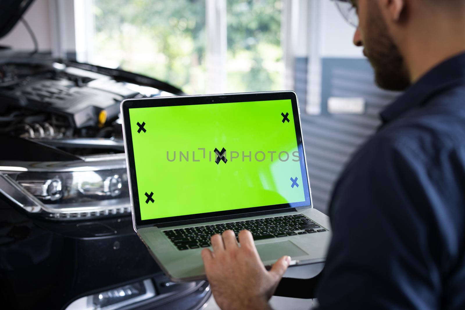 Car service mechanic uses laptop computer with green screen mock up chroma key car diagnostic software. Car Scanner Computer Diagnostics. Automotive Electronic Diagnostic.