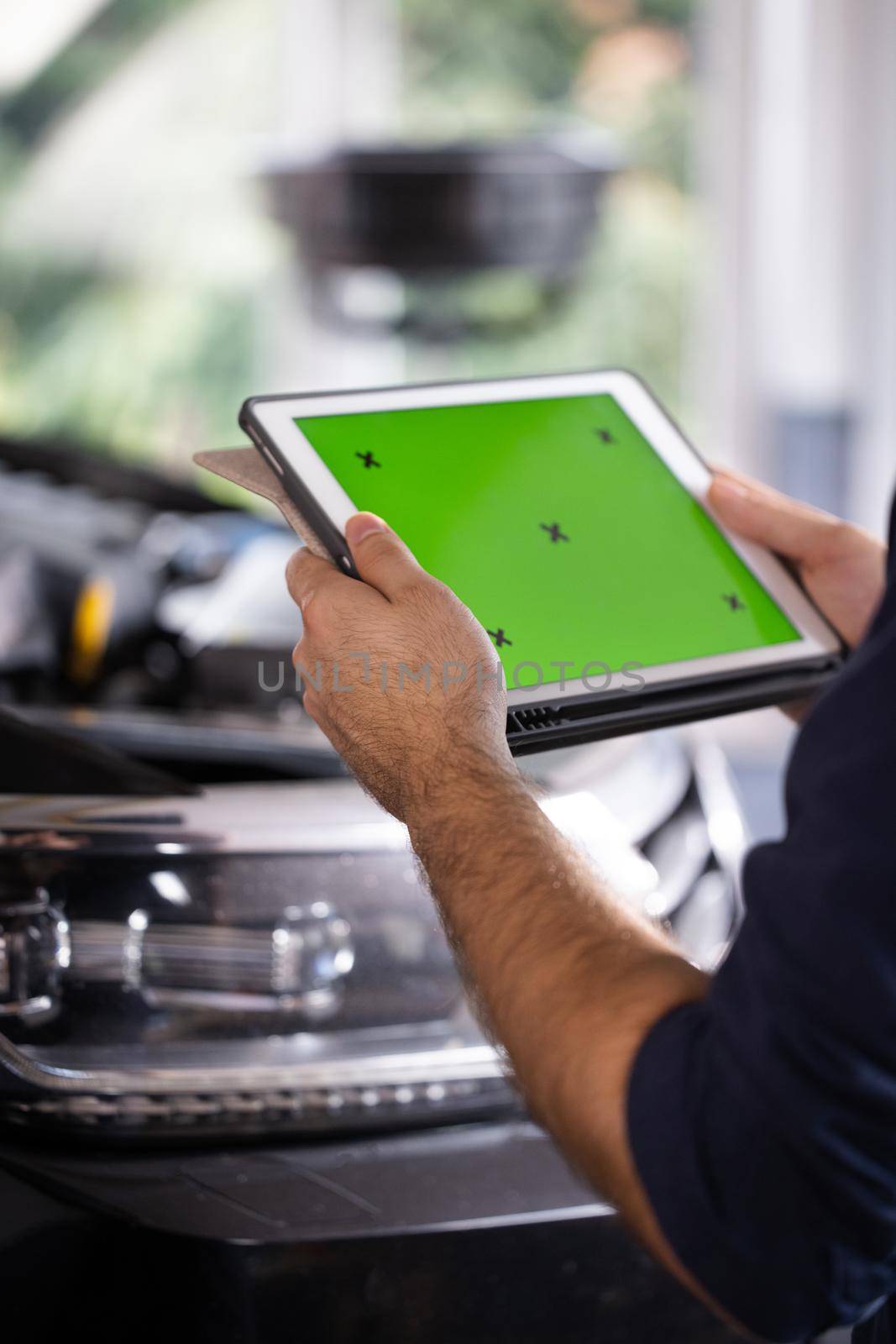 Car Service Mechanic Uses Tablet Computer with Green Screen Mock Up Chroma Key that is Pointed at an Enginer Bay. Specialist Inspecting the Vehicle in Order to Find Broken Components