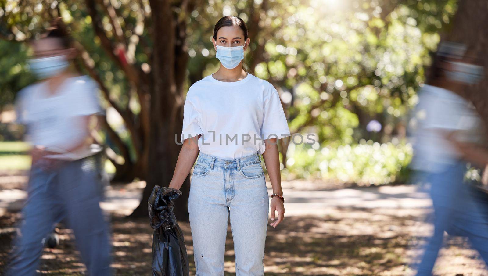 Female wearing covid mask cleaning the park for a clean, hygiene and safe green outdoor environment. Community service, volunteers or activist workers with rubbish, trash and garbage in a plastic bag.