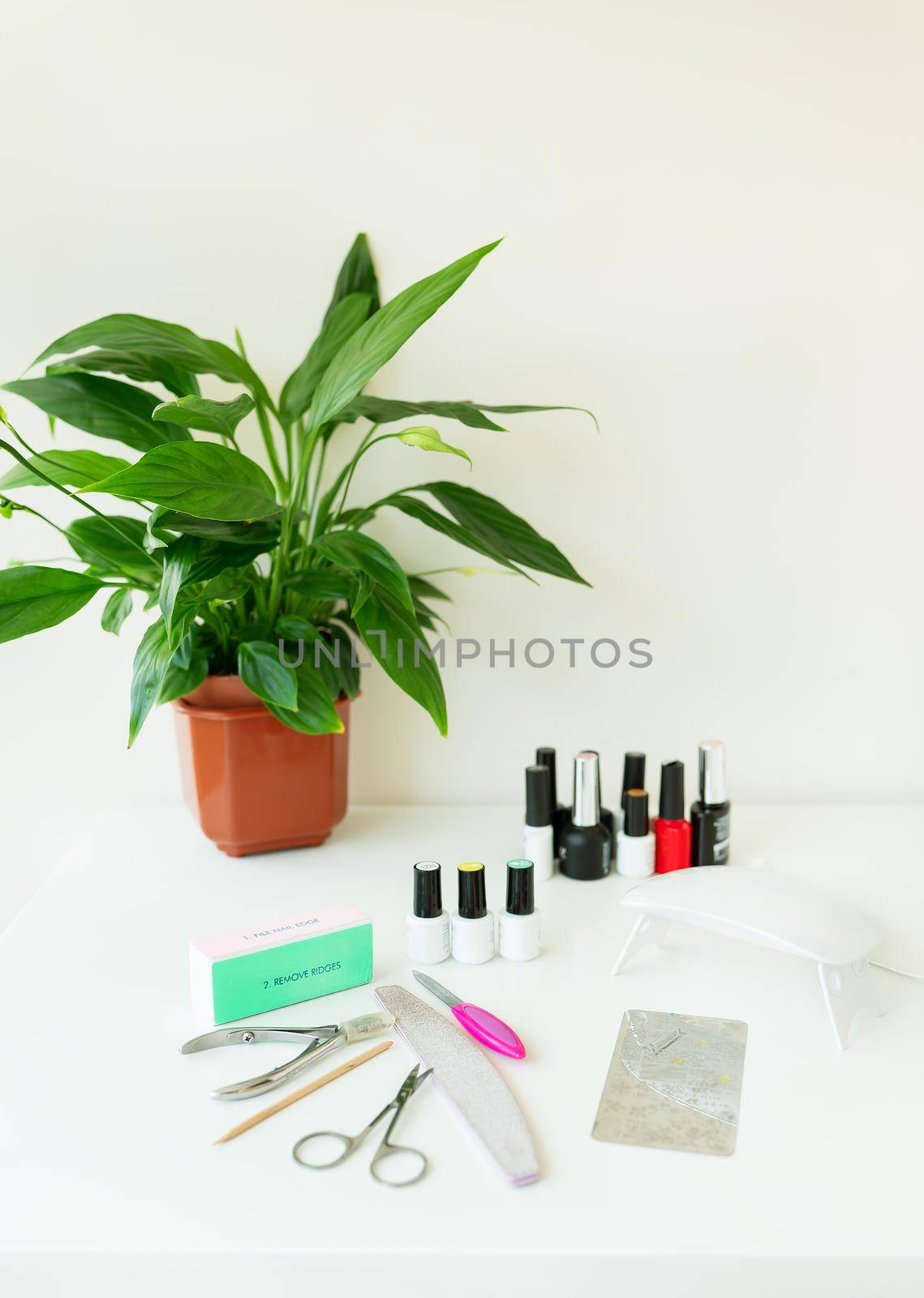 Nail salon workspace concept. Top view female hands and manicure tools on pink background. Beauty treatment and hand care