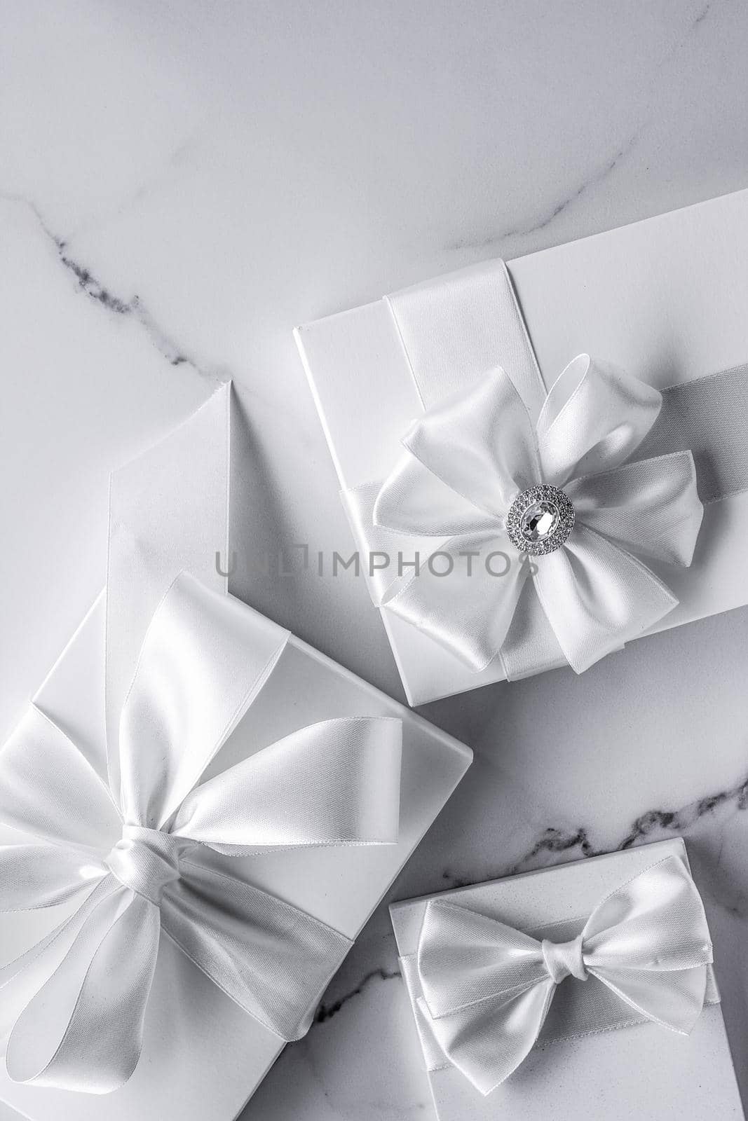 Romantic celebration, bridal decor and holiday present concept - Luxury wedding gifts with silk bow and ribbons on marble background