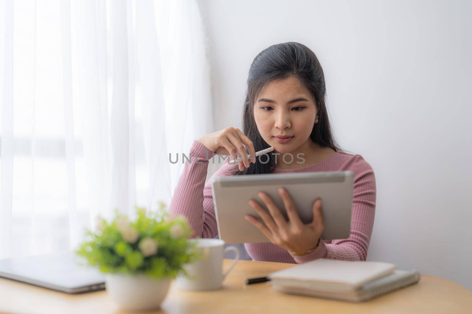 Young asian woman using digital tablet at home. Online learning, home school concept. by nateemee