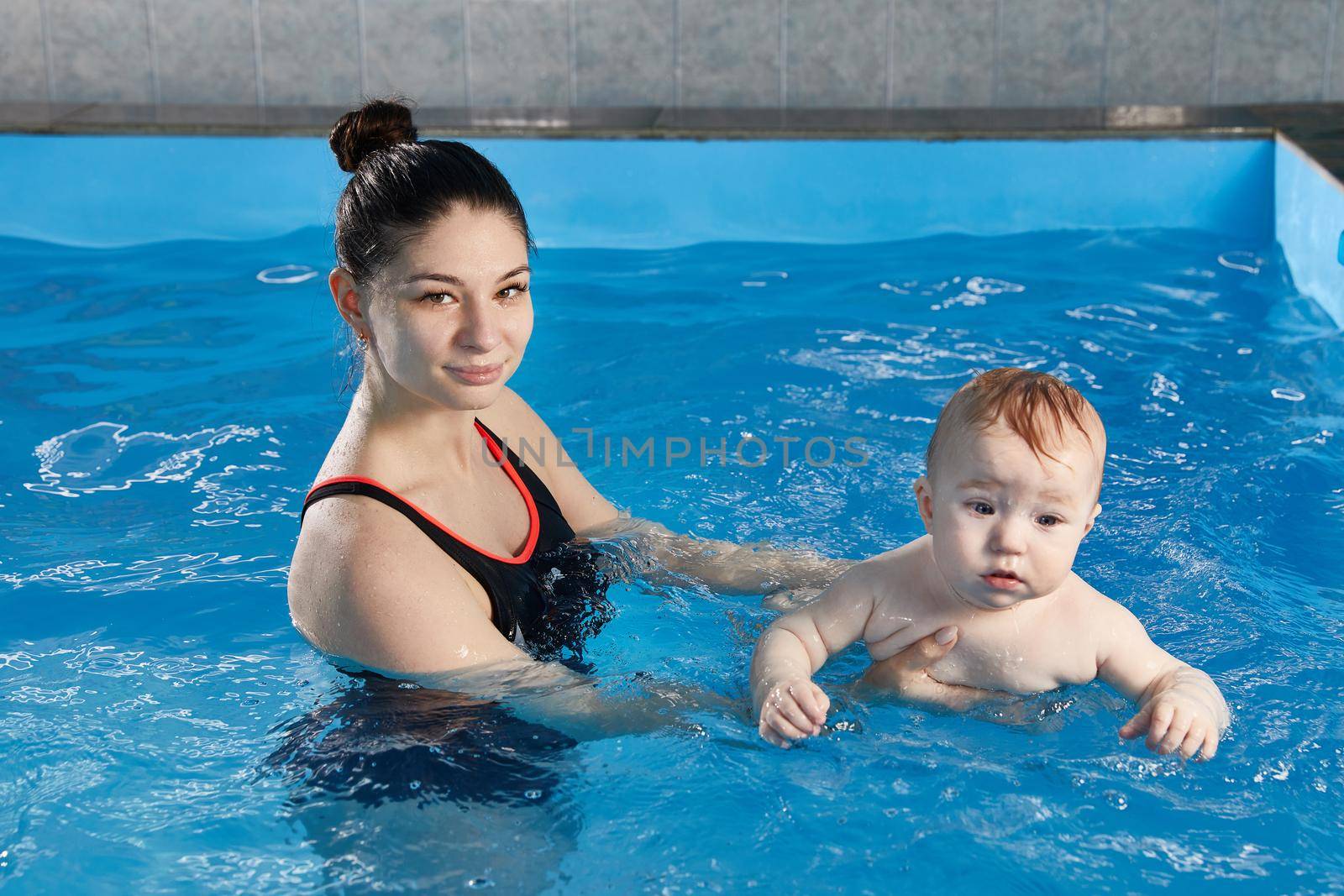 Little baby learning to swim in pool with teacher by Mariakray