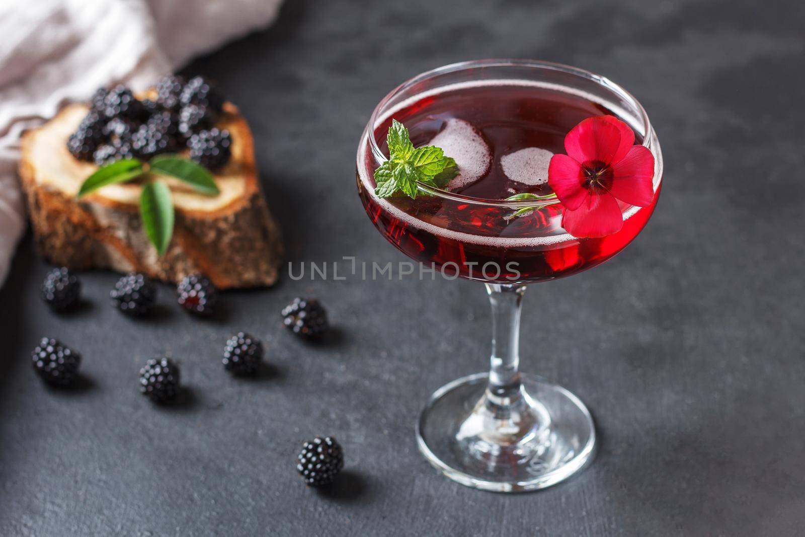 Refreshing lemonade with blackberries, ice and mint on a black background.