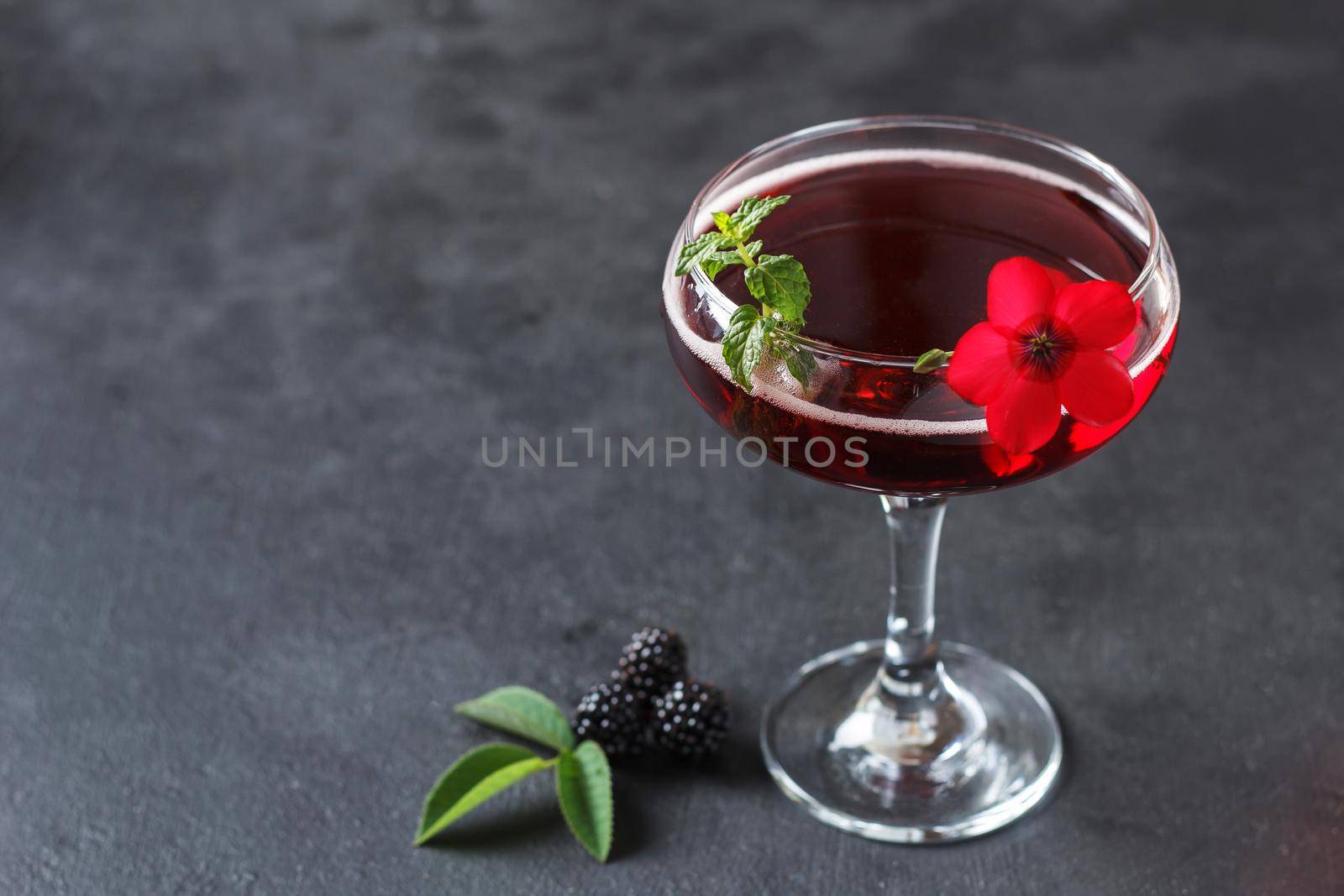 Refreshing lemonade with blackberries, ice and mint on a black background. Copy space