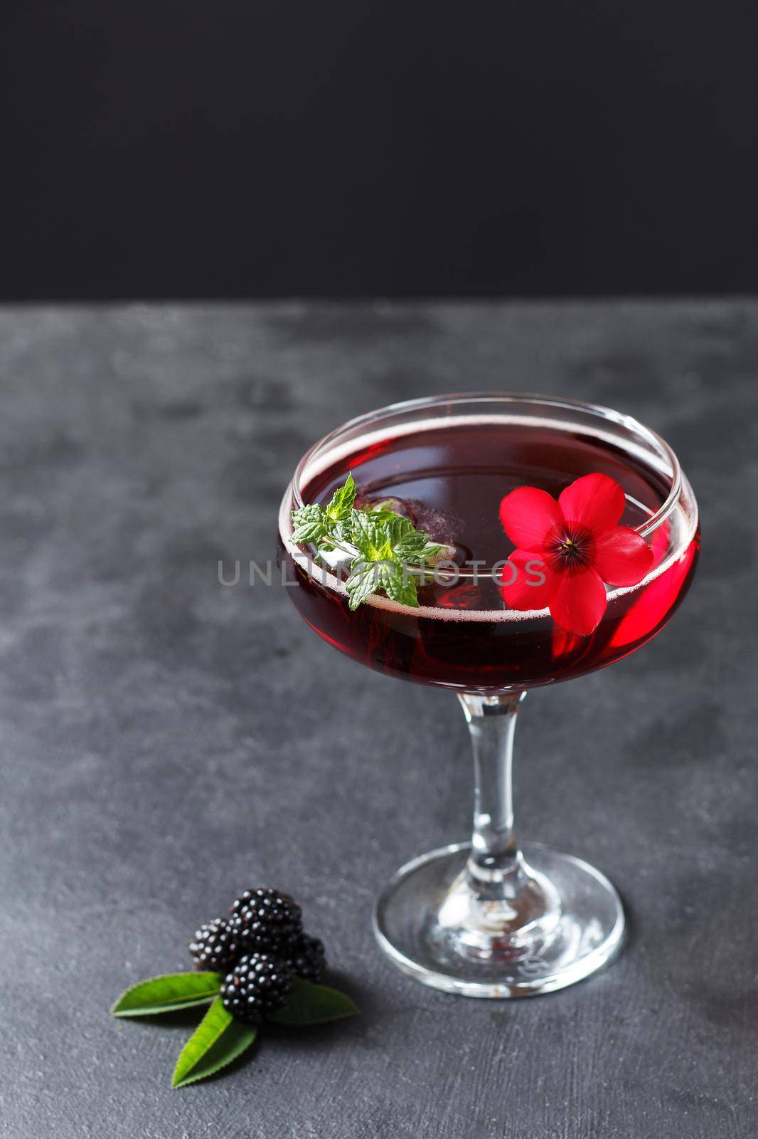 Refreshing lemonade with blackberries, ice and mint on a black background. Copy space,vertical photo