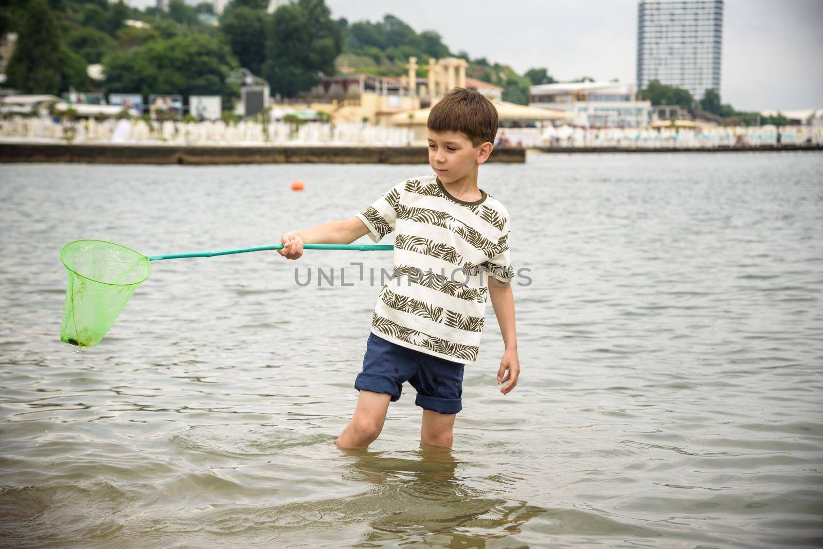 One little boy alone exploring the beach at low tide walking towards the sea coast. happy childhood concept.