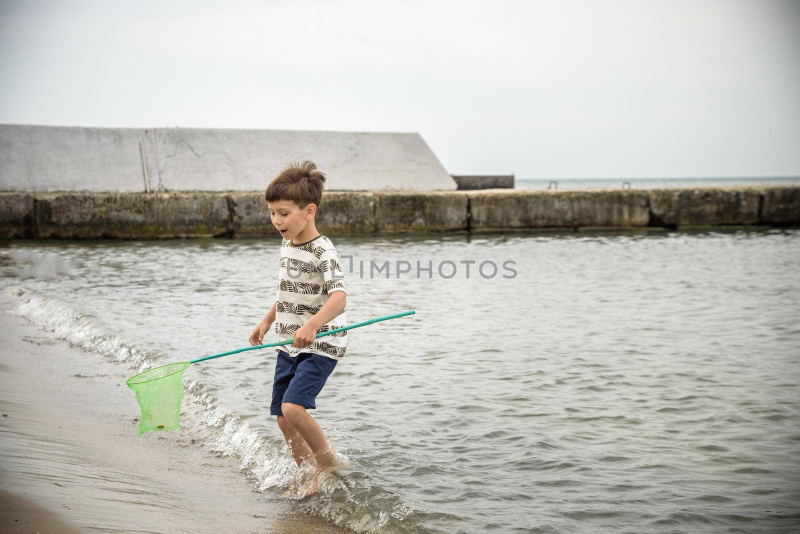 One little boy alone exploring the beach at low tide walking towards the sea coast. happy childhood concept.